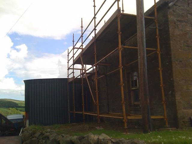 Scaffolding erected to the gable end of a stone building under construction